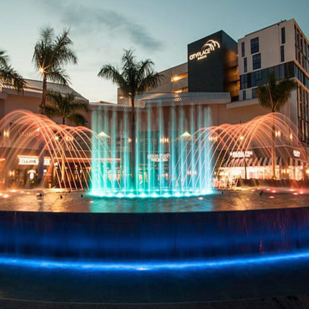 Water Fountain with lights in a pool with buildings in the background